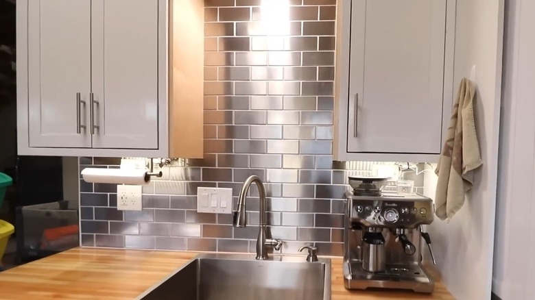 A close up of a sink with a stainless steel backsplash.