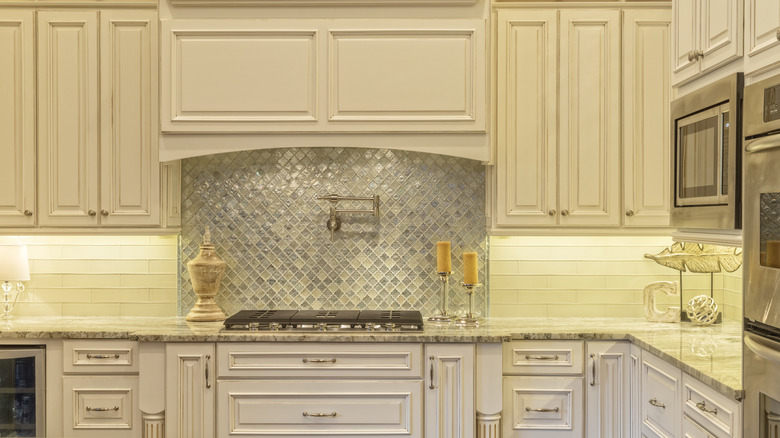 A cream kitchen with a blue glazed glass, mosaic backsplash.