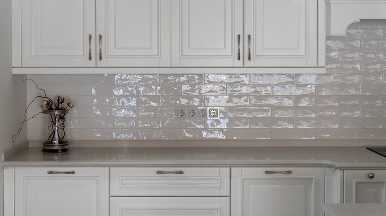 A white kitchen with a horizontal porcelain tile, subway backsplash.