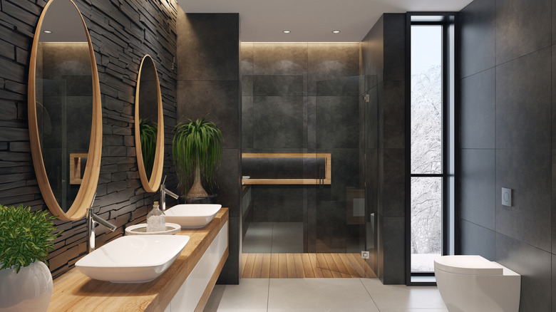 A dark bathroom with slate textured walls and wooden accents.