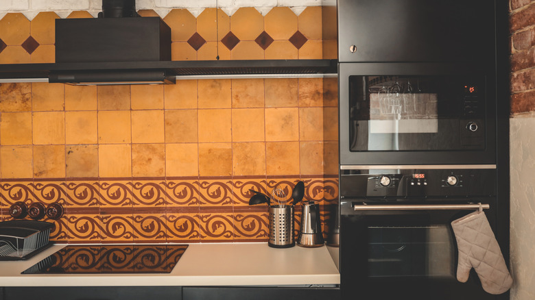 A kitchen with patterned terracotta tile walls.