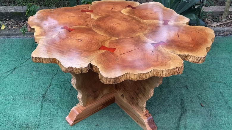 Custom made wood table made from multiple sections of tree stumps joined together in a table top and legs on an outdoor rug