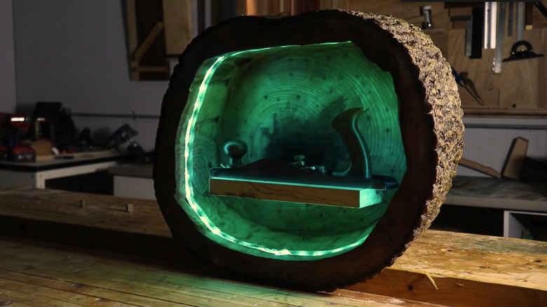 Hollowed out tree stump shelf with green LED lights on a bench in a workshop