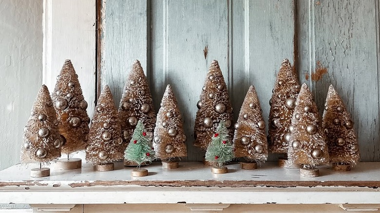 Vintage gold and green bottle brush trees places over a mantlepiece.