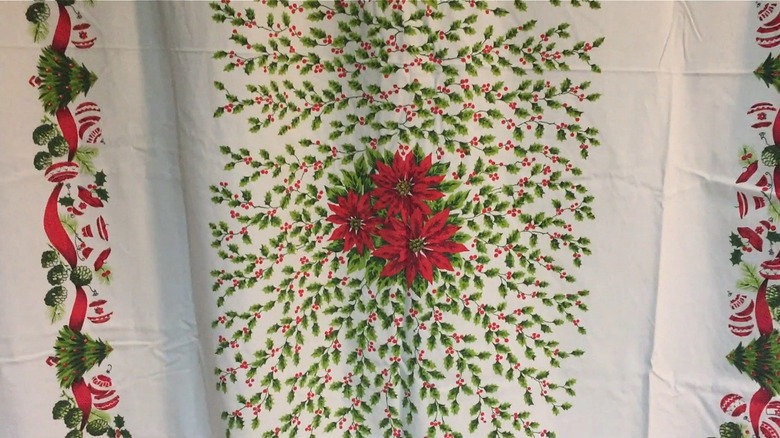 A vintage tablecloth with a Christmas mistletoe and poinsettias pattern.