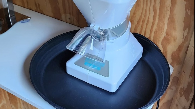 A snow cone machine on top of oil drip pan.