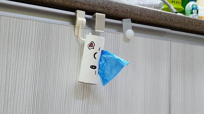 A decorated trash bag dispenser with a cardboard tube.