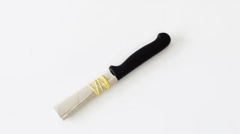 A black knife with a cardboard sheath.
