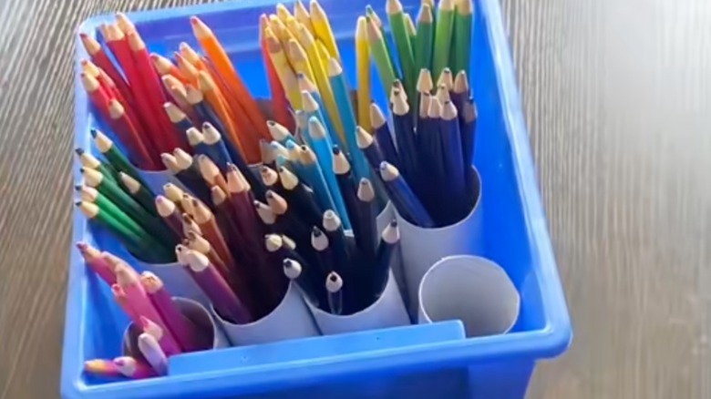 A blue box filled with colored pencils sorted by rolls.