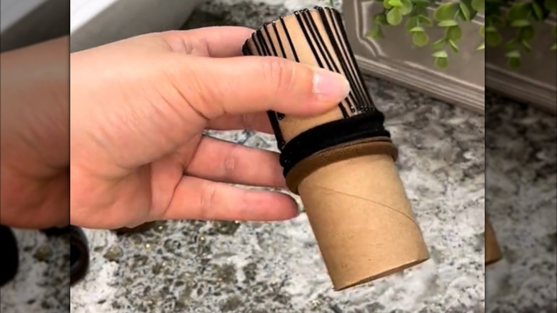 A toilet paper roll holding bobby pins and hair ties.