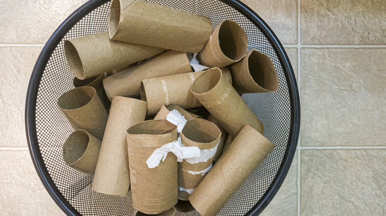 Rolls of toilet paper in black trash can.
