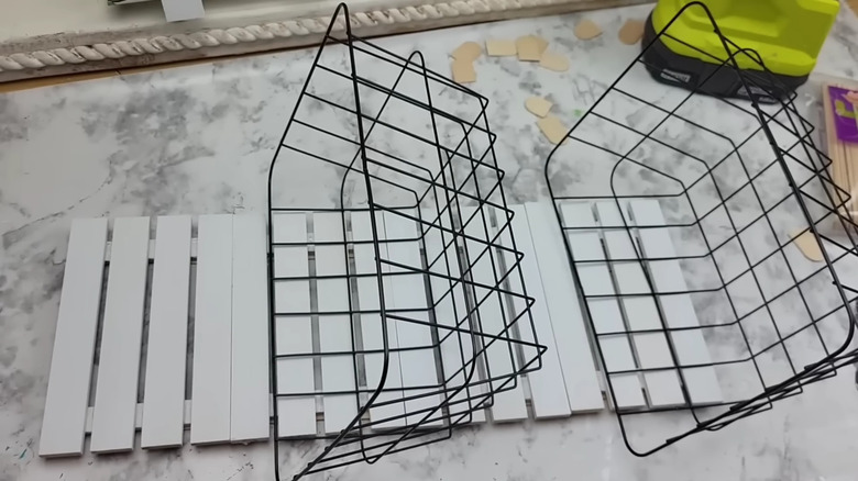 Mini pallets connected and holding a black wire basket with oranges inside