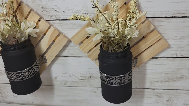 Two wall decor displays made with mini pallets and jars painted black with florals inside
