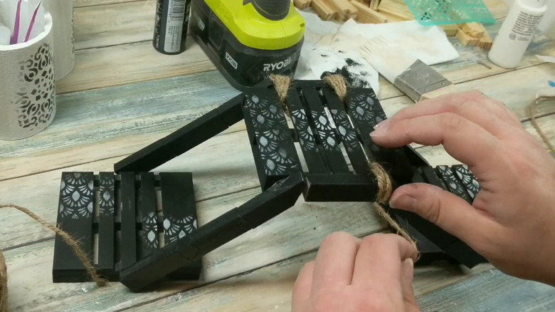 Creator tying twine around the top tier of the elevated pallet stand