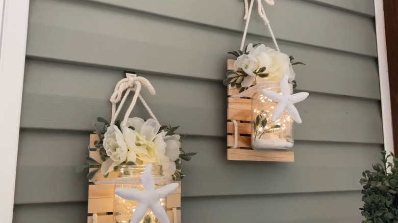 Hanging display made with mini pallets and a jar filled with beach-themed items and fairy lights