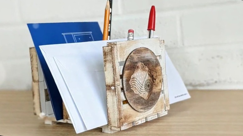 Pallet desk organizer with an aged finish holding envelopes and writing utensils