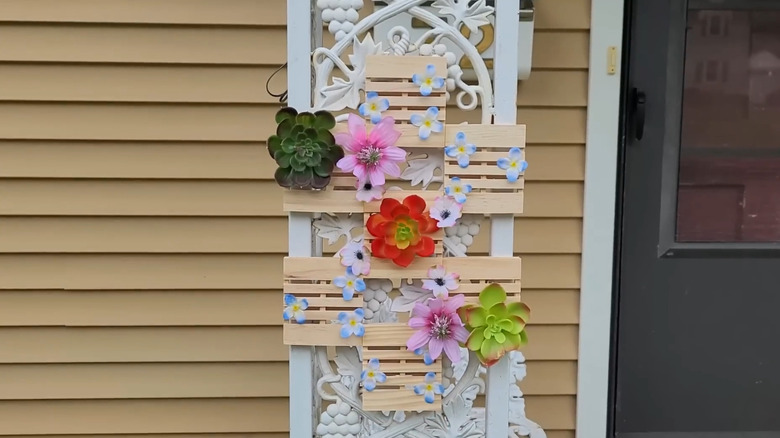 Mini pallets connected in a staggered pattern with artificial flowers attached