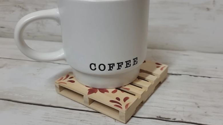 Mini Dollar Tree pallet with designs stenciled on it and a coffee cup sitting on top