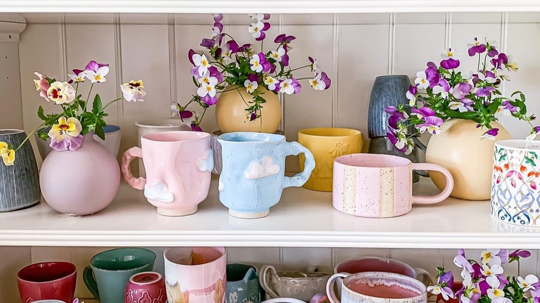 Coffee mugs with cut flowers on a shelf