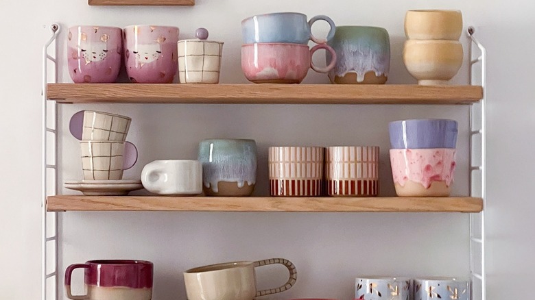 Colorful mugs on a wooden shelf