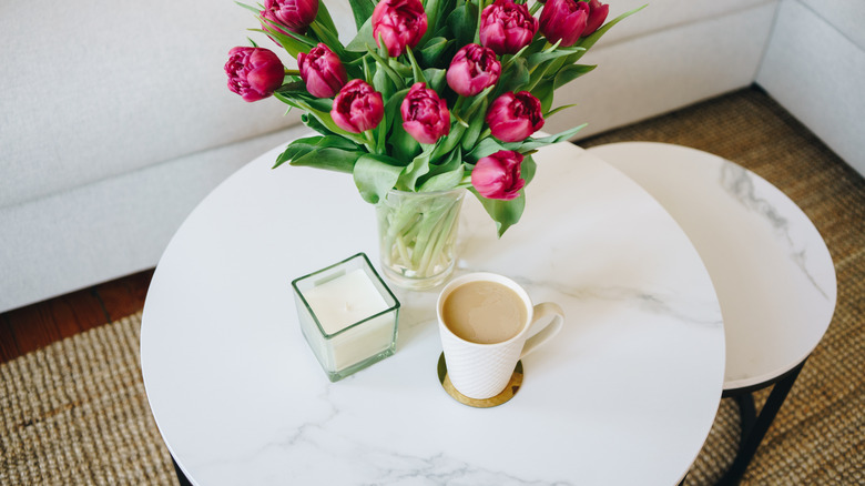 A marble coffee table with a vase filled with fresh-cut pink tulips.