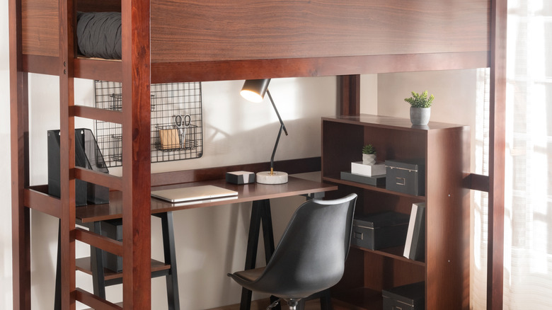 A wooden bunk bed with an workspace underneath.