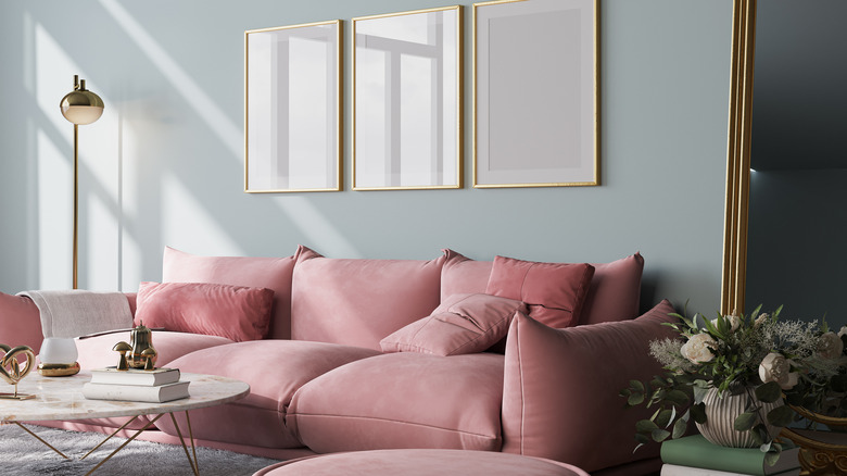 A blush-pink sofa in a living room with gold-accented fixtures.