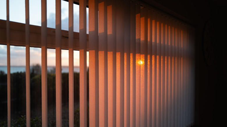 Vertical blinds with the sunset shining through them.