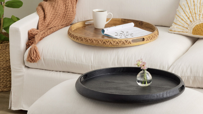 Wood ottoman tray on a cream-colored sofa holding a small vase