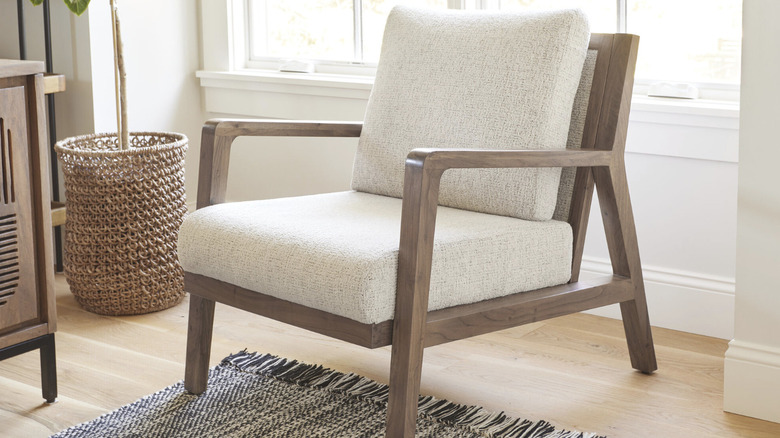 Upholstered acacia wood chair from World Market in a living room next to a potted tree