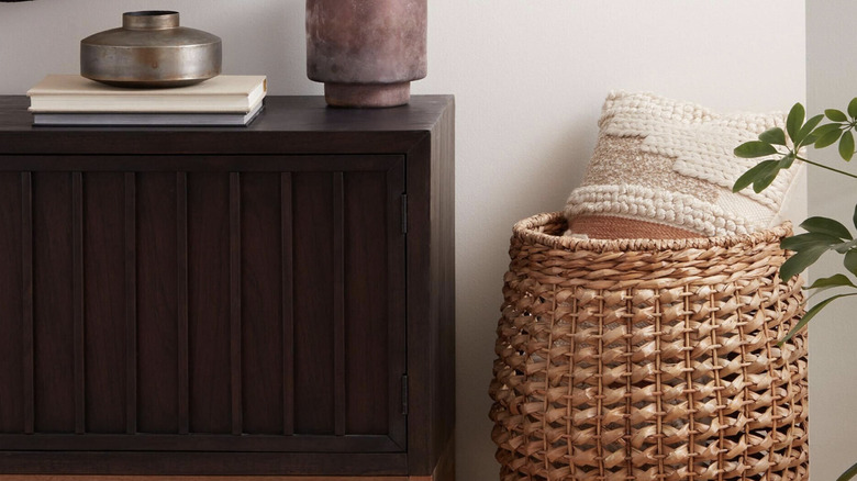 Indoor/outdoor lumbar pillow in a woven basket by door