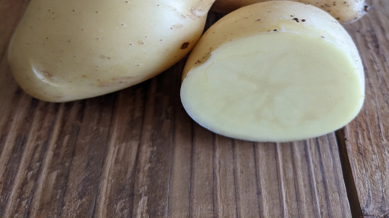 A close up of the 'Bintje' potato sitting on a table, with one being cut open