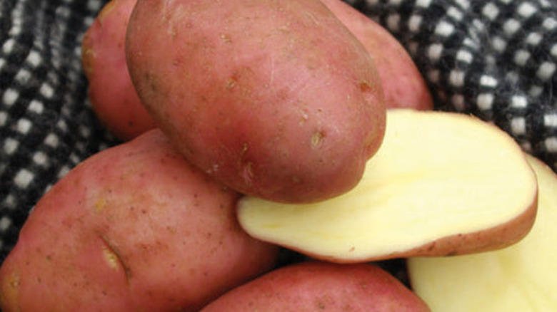 Desire potatoes, with some cut open, on a checkered towel