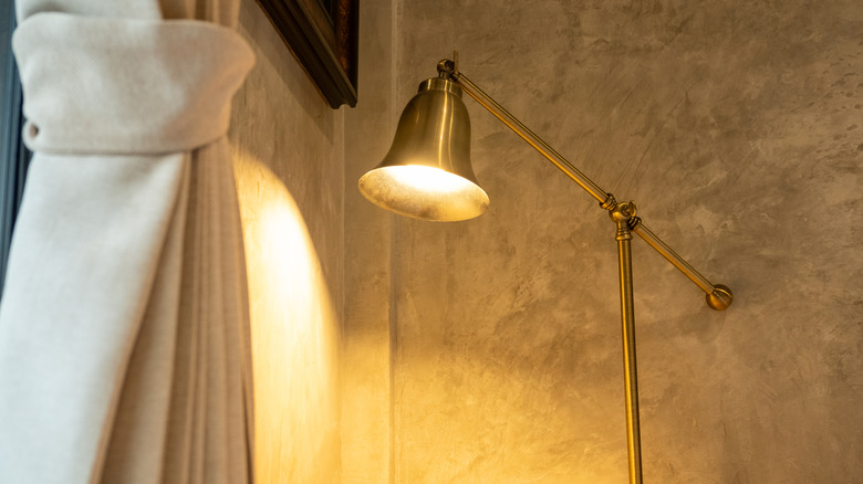 A lit brass lamp next to a curtain.