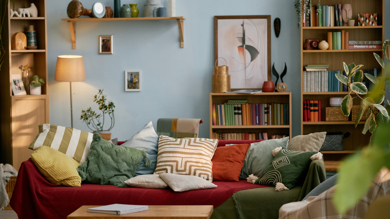 Three bookshelves full of items behind red couch.