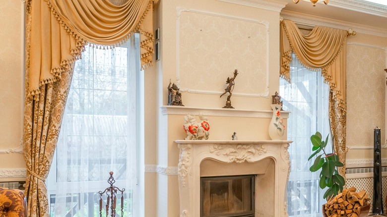 Cream designed drapes with tassels next to fireplace.
