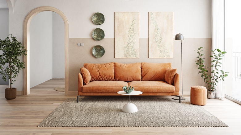 A living room with a tan couch and wall art.