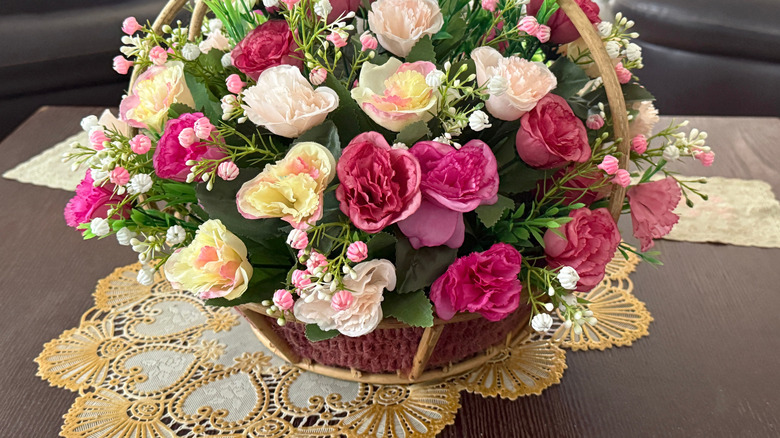 A yellow and white doily under a flower arrangement.