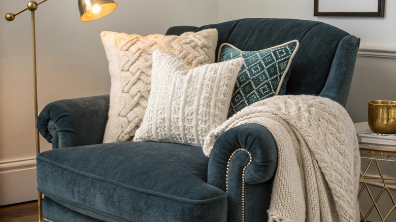 Three large cream and blue pillows on glue armchair.