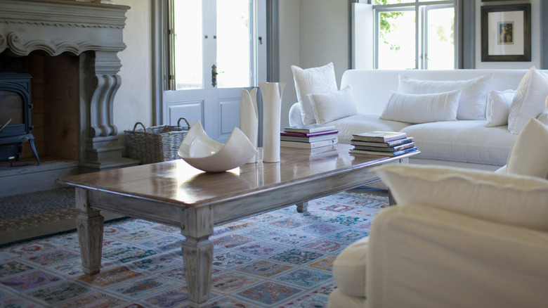 A large grey wood coffee table by white couches.