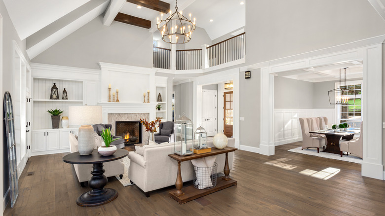 A formal white living room  with a lit fireplace.