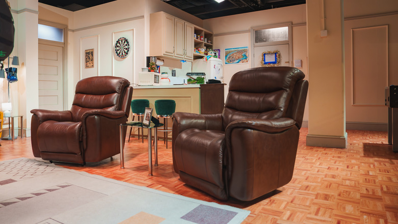 Two large, brown leather recliners on wood floor.