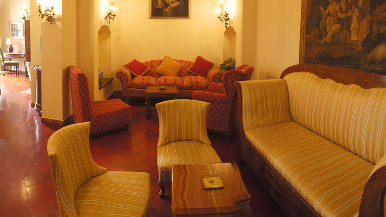 A large living room with red couches, bright artificial light, and overall moody Tuscan decor vibe