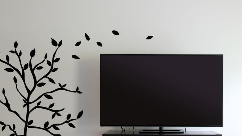 Black vinyl wall decal of tree beside a television