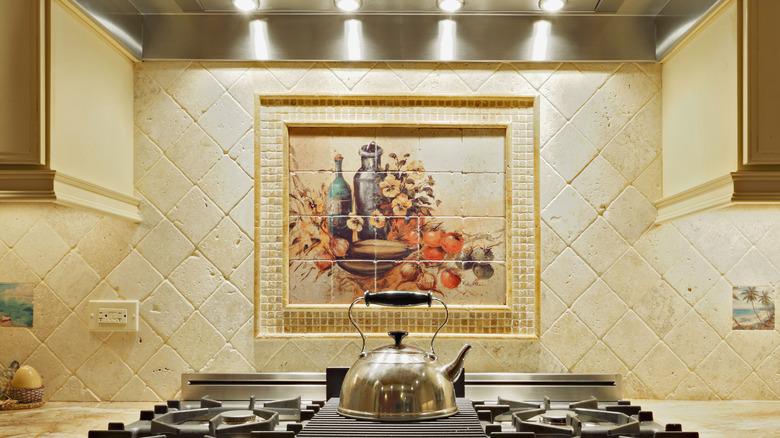 A painted and framed square tile behind a backsplash with smaller squares as a frame against a diagonal square tile in the kitchen