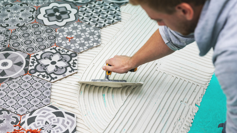 A man installs pattern hexagonal tiles on a bathroom floor