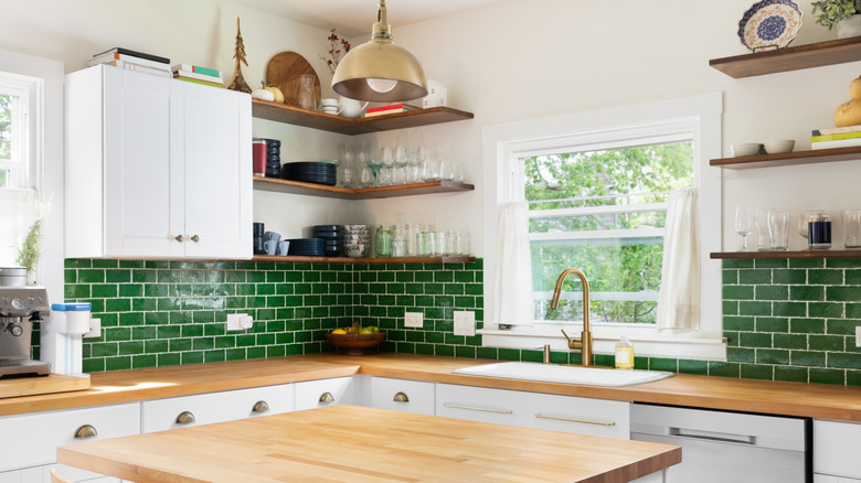 A kitchen with green subway tile backsplash and white cabinets