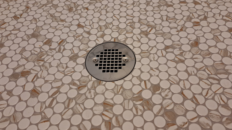 A series of patterned penny rounds with beige brown surrounding a shower drain
