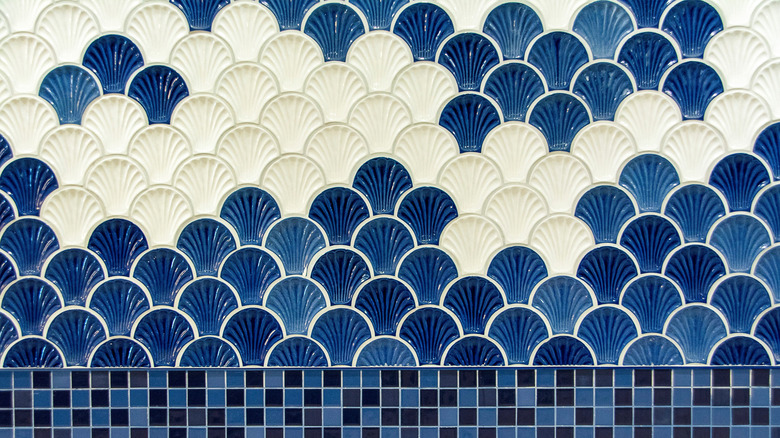 Scalloped tiles with seashell shapes in white and blue. with black and blue small square tiles underneath.