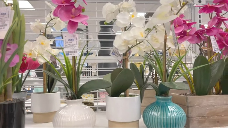 Collection of pink and white artificial flowers in various small vases